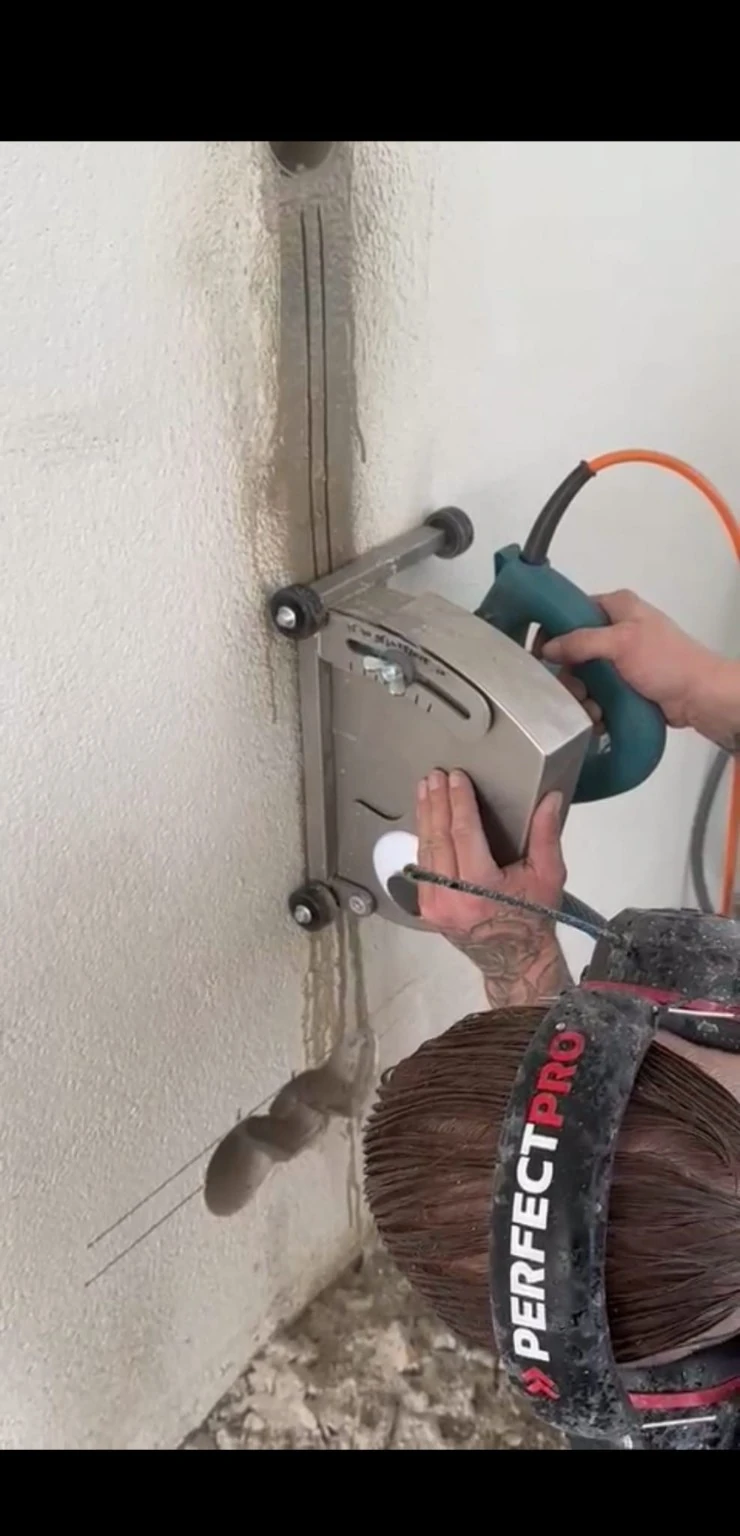 Een muurfrees volgt een verticale leidinggoot in de wand